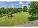 Expansive backyard featuring a lush green lawn, mature trees, and a play structure for outdoor fun and recreation at 369 Parker Rd, Mcdonough, GA 30252