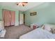 Bright bedroom featuring plush carpeting, a ceiling fan, and a closet concealed behind charming floral curtains at 369 Parker Rd, Mcdonough, GA 30252