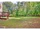 View of a large backyard area, adjacent to an upper wooden deck and with mature trees and green grass at 145 Driftwood Trl, Fayetteville, GA 30215