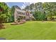 Two-story home with a brick and light yellow facade, large lawn, and mature trees at 145 Driftwood Trl, Fayetteville, GA 30215