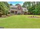 Two-story brick home with a manicured front lawn, porch with rocking chairs, and shuttered windows at 145 Driftwood Trl, Fayetteville, GA 30215