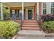 Close-up of a brick home's front porch, featuring rocking chairs, a decorated door, and lush greenery at 145 Driftwood Trl, Fayetteville, GA 30215