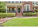 Charming brick home featuring a covered porch with rocking chairs, an elegant front door, and manicured landscaping at 145 Driftwood Trl, Fayetteville, GA 30215