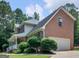 Exterior angle showcasing a red brick home with white siding, lush greenery, and a two-car garage at 416 River Forest Dr, Mcdonough, GA 30252