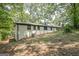 Back exterior of home with white brick and dark trim, on a sloped lot with trees at 3833 Bakers Ferry Sw Rd, Atlanta, GA 30331