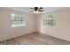 Bright bedroom featuring two windows, wood-look floors, and a ceiling fan for comfortable living at 107 Club Dr, Locust Grove, GA 30248