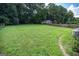 Large grassy backyard with a storage building, mature trees, and wood fence at 6233 Castlewood Dr, Morrow, GA 30260