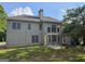 View of the house's back exterior featuring a yard, patio, lots of windows, and neutral toned siding at 7235 Thoreau Cir, Atlanta, GA 30349