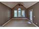 Large bedroom with vaulted ceiling, carpeted floor, a ceiling fan, and multiple windows overlooking the backyard at 7235 Thoreau Cir, Atlanta, GA 30349