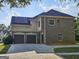 Exterior view of a brick home featuring a three car garage, stucco accents, and solar panels at 7235 Thoreau Cir, Atlanta, GA 30349