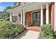 Inviting front porch with columns and brick flooring, enhanced by lush landscaping at 100 Old Plantation Way, Fayetteville, GA 30214
