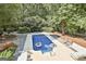 Aerial view of a backyard swimming pool surrounded by mature trees and outdoor furniture at 100 Old Plantation Way, Fayetteville, GA 30214