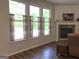 Bright living room featuring a stone fireplace, hardwood floors, and three windows offering ample natural light at 85 Crabapple Ridge Dr, Oxford, GA 30054