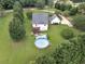 Aerial view of a backyard with an above ground pool, wooden deck, green grass, and mature trees at 2110 Mcgarity Rd, Mcdonough, GA 30252