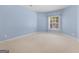 Bright bedroom with neutral carpet, a large window with natural light, and soft blue walls at 5297 Heron Bay Blvd, Locust Grove, GA 30248