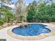 Relaxing pool area with a captivating waterfall, lush greenery, and towering trees, creating a tranquil retreat at 5297 Heron Bay Blvd, Locust Grove, GA 30248