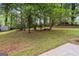 Expansive backyard with mature trees, a storage shed, and lush green grass at 954 Camp Creek Sw Dr, Lilburn, GA 30047