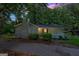 A charming single-story home with a brick chimney and covered porch, illuminated in the evening light at 6770 Burkhead Dr, Union City, GA 30291