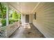 Covered front porch featuring white lattice railing, gray siding, and a gray front door with leafy foliage nearby at 6770 Burkhead Dr, Union City, GA 30291