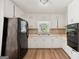 Functional kitchen featuring white cabinets, a black refrigerator, laminate floors, and a window above the sink at 6770 Burkhead Dr, Union City, GA 30291