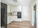 Well-lit kitchen with white cabinetry, black appliances, laminate floors, and access to an additional room at 6770 Burkhead Dr, Union City, GA 30291