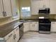 Modern kitchen featuring stainless steel appliances, white cabinets, and laminate flooring at 4199 Elderberry Nw Dr, Acworth, GA 30101
