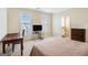 A sunlit bedroom with two windows, a desk, a television and an ensuite bathroom at 110 Camford Stone Path, Fayetteville, GA 30214