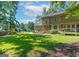 A view of the house and expansive green backyard is framed by mature trees at 200 Savannah Walk, Peachtree City, GA 30269