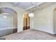Spacious living room with plush carpeting, decorative chandeliers, arched entries, and coffered ceilings, bathed in natural light at 2817 Village Park E Dr, Ellenwood, GA 30294