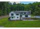 A charming two-story home with gray shingled roof and stone accents nestled in a lush green yard with mature trees at 360 Darren Dr, Fayetteville, GA 30215