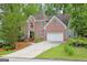 Charming two-story brick home with a two-car garage and landscaped front yard nestled amongst mature trees at 7435 Woodruff Way, Stone Mountain, GA 30087
