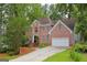 Charming two-story brick home with a two-car garage and landscaped front yard nestled amongst mature trees at 7435 Woodruff Way, Stone Mountain, GA 30087