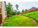 Expansive backyard view featuring a lush lawn, mature trees, and a retaining wall at 4311 Hampton Mill Pkwy, Douglasville, GA 30135
