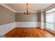 Empty dining room with hardwood floors, chandelier, wainscoting, and a large window at 4311 Hampton Mill Pkwy, Douglasville, GA 30135