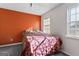 Bedroom featuring an orange accent wall, carpet floors, and two windows with natural light at 453 Camp Hill Ln, Jonesboro, GA 30238