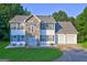 Charming two-story home featuring stone accents, blue shutters, a three-car garage, and a well-maintained front yard at 1067 Misty Meadows Pt, Hampton, GA 30228