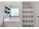 Bright bathroom featuring a soaking tub under a window and a separate shower with a striped curtain at 470 Louise Way, Locust Grove, GA 30248