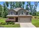 Charming two-story home with a brick-accented front and attached two-car garage, set against a backdrop of lush greenery at 470 Louise Way, Locust Grove, GA 30248