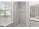A bright bathroom featuring a large window and a stand-up shower with white tile surround at 380 Peach Drive, Mcdonough, GA 30253
