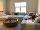Spacious living room featuring a sectional sofa, large window and round wooden coffee table at 160 Elysian Dr, Fayetteville, GA 30214