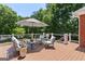 Relaxing outdoor deck with stylish patio furniture, shade umbrella, and a view of the surrounding trees at 660 Milton Dr, Mcdonough, GA 30252