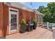 Back deck with a grill and green plants by a door and windows at 660 Milton Dr, Mcdonough, GA 30252