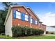 Side view of a red brick home with blue shutters, a manicured lawn, and mature shrubbery at 3796 Wolverton Cir, Lithonia, GA 30038