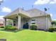 A well-maintained backyard with a brick house, lush lawn, flowerbeds and a covered patio with an outdoor grill at 409 Brandy Ln, Mcdonough, GA 30253