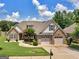 An inviting exterior featuring stone accents, a manicured lawn, a blooming tree, and an attached two-car garage at 409 Brandy Ln, Mcdonough, GA 30253
