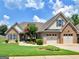 Charming brick and siding home featuring a manicured lawn, blossoming trees, and a two-car garage at 409 Brandy Ln, Mcdonough, GA 30253