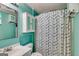 Bright bathroom featuring aqua walls, a white vanity, medicine cabinet, toilet, and a shower with patterned curtain at 169 Knights Ct, Dallas, GA 30157