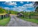 Stone entrance with black metal gate surrounded by a beautiful green lawn and mature trees at 540 Benton Rd, Covington, GA 30014