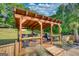 Wooden outdoor kitchen with bar seating is surrounded by a lush green landscape at 540 Benton Rd, Covington, GA 30014
