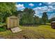 Yellow shed in the backyard with adjacent three-rail fence and mature trees at 540 Benton Rd, Covington, GA 30014